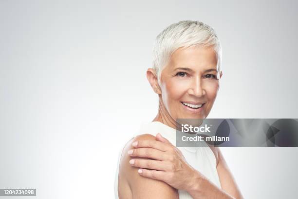 Schöne Lächelnde Seniorin Mit Kurzen Grauen Haaren Posiert Vor Grauem Hintergrund Schönheit Fotografie Stockfoto und mehr Bilder von Frauen über 40