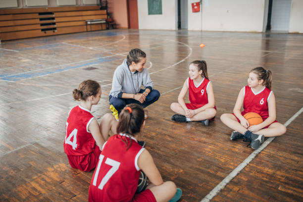 istock Female coach sitting with basketball team 1204236433