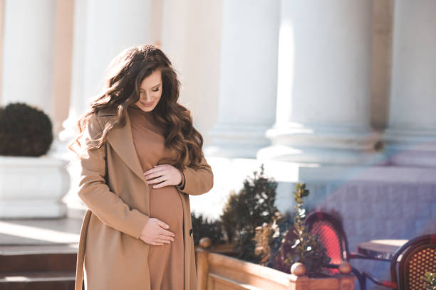 pregnant woman posing outdoors - coat warm clothing one person joy imagens e fotografias de stock