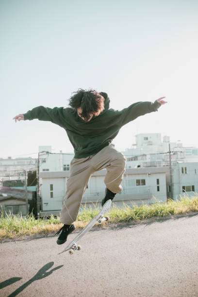 Portrait of Asian Skater Candid full length portrait of skateboarder on a city street. Ollie stock pictures, royalty-free photos & images