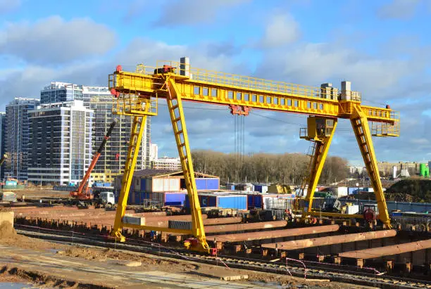 Photo of Gantry crane and auto crane working at construction site