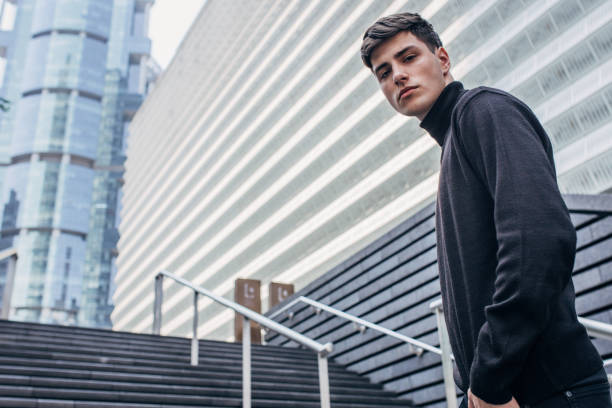 istock Handsome man in black clothing standing on stairs 1204239074