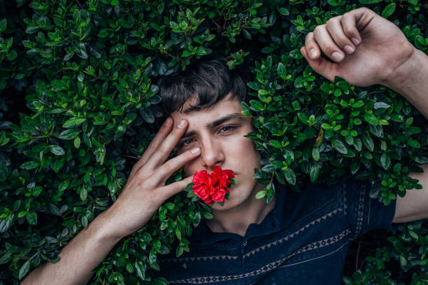 Young Hispanic man with half blonde hair with a bouquet of purple flowers with copyspace