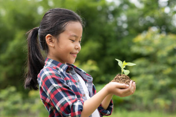 istock Asian girl standing and hold the tree planted 1204240194