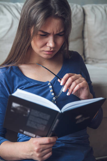 istock Woman with glasses reading a book 1204240330