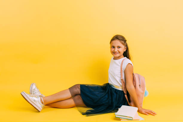 écolière adolescente heureuse avec des livres sur un fond jaune - schoolgirl child backpack book bag photos et images de collection