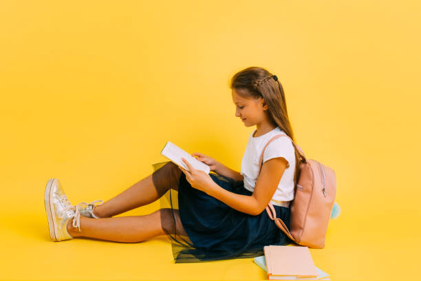 adolescente intelligente dans des vêtements d’école faisant des devoirs affichant un livre - schoolgirl child backpack book bag photos et images de collection