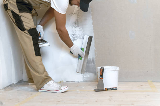 istock Male painter with a putty knife in his hands makes repairs in th 1204244232