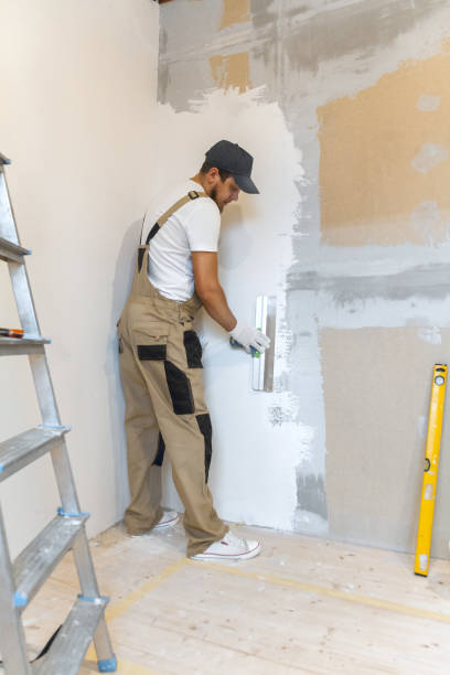 istock Male painter with a putty knife in his hands makes repairs in th 1204244263