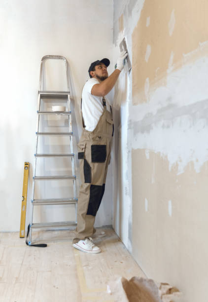 istock Male painter with a putty knife in his hands makes repairs in th 1204244366