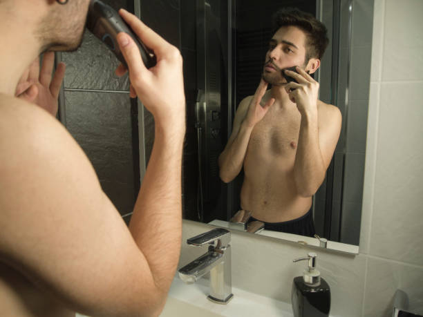 ritratto di bell'uomo caucasico riflessione da dello specchio, rasatura con un rasoio - shaving men electric razor reflection foto e immagini stock