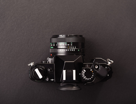 Top view of a professional vintage SLR analog film camera on black background
