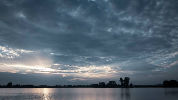 istock The sun shines through the blue clouds above the water 1204254046