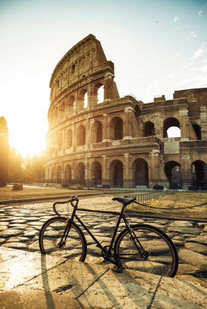 vélo par le colisée de rome dans un jour de soleil chaud d’été: vacances en italie - light nobody coliseum vertical photos et images de collection