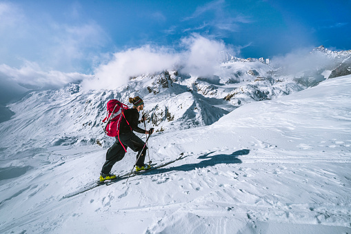 Ski mountaineer ascends snowy mountain ridge line