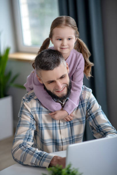 istock Joyful young dad, little daughter smiling looking at a laptop. 1204258641