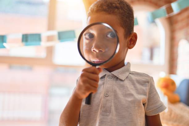 красивый афро-американский малыш, играющий с лупой в детском саду - curiosity searching discovery home interior стоковые фото и изображения