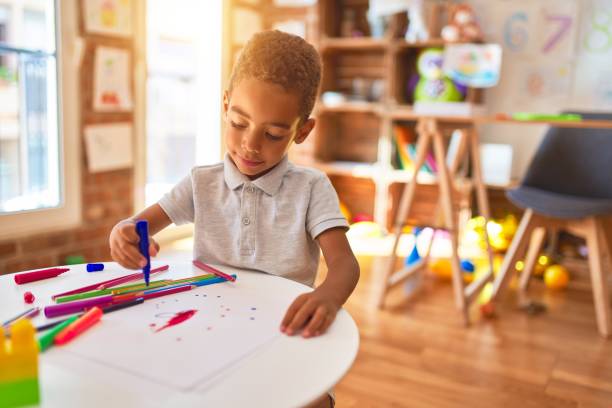 beau dessin d’enfant en bas âge d’américain africain utilisant le papier et le stylo de marqueur à la maternelle - little boys preschooler child learning photos et images de collection