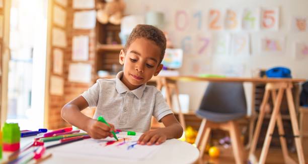 hermoso dibujo de niño afroamericano usando papel y pluma marcador a la guardería - preschooler fotografías e imágenes de stock