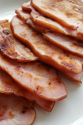 slices of Canadian back bacon in a pile on a white plate