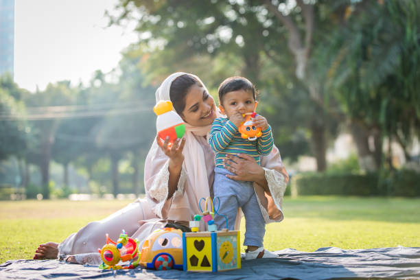 Arabic mom and her little toddler playing outdoors Middle eastern family with traditional dress having fun outdoors - Modern islamic mom and son in Dubai arab culture photos stock pictures, royalty-free photos & images
