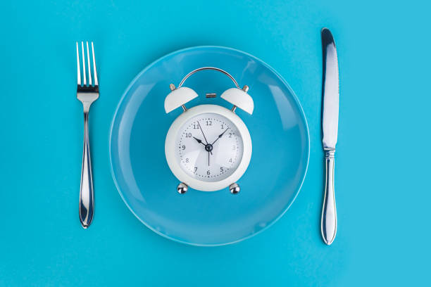 istock Alarm clock with fork and knife on the table. Time to eat, Breakfast, Lunch Time and Dinner concept 1204263096