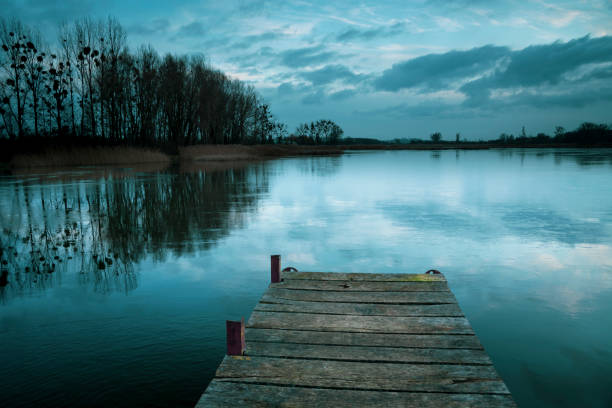 istock Cloudy and cold winter evening, freezing lake with a pier 1204264057