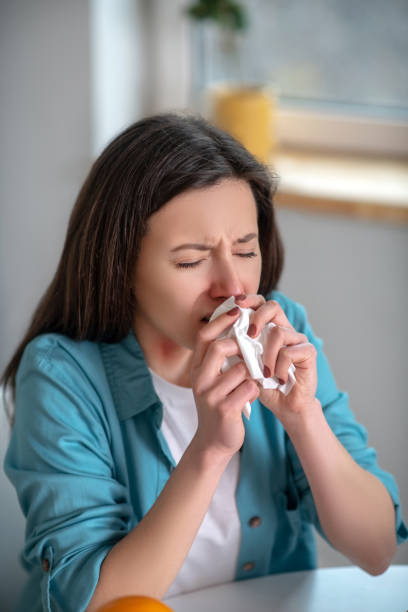 istock Young woman sneezing and using a napkin 1204266575