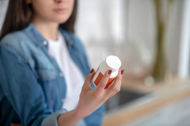 istock Young woman holding a container with pills 1204266700