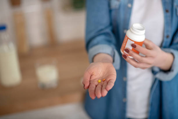 istock Woman holding two pills and a container in hands 1204266722