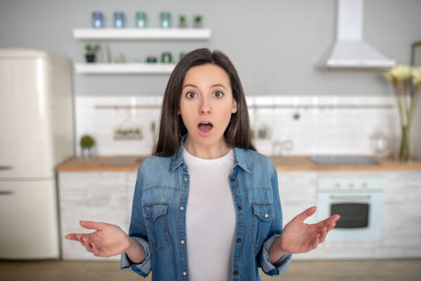 istock Surprised young woman standing in her kitchen 1204267330