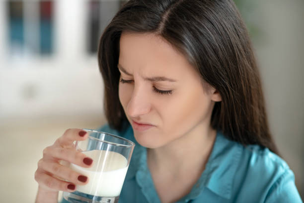istock Woman drinking a glass of milk unwillingly 1204267434