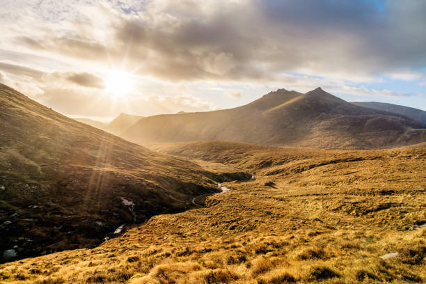 istock Dramatic sunset with sunrays in beautiful autumn coloured valley with river in Mourne Mountains 1204268339