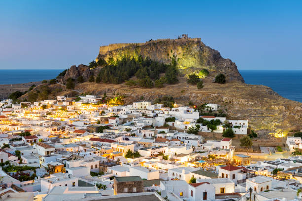 telhados brancos de lindos com a acrópole de lindos, rodes, dodecanese, ilhas gregas, grécia, europa - sea aegean sea night illuminated - fotografias e filmes do acervo