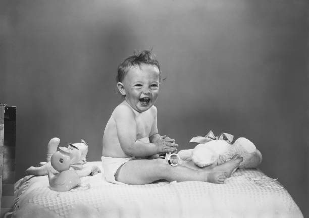 Baby boy sitting on bed with toys, laughing  animal representation photos stock pictures, royalty-free photos & images