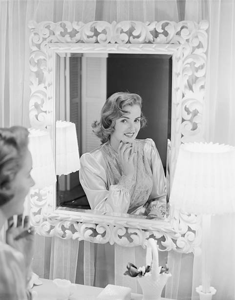 Young woman looking in mirror, smiling  1952 1952 stock pictures, royalty-free photos & images