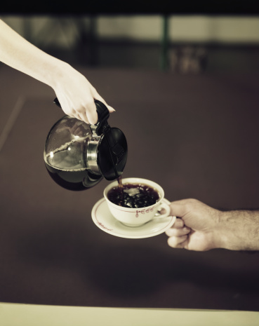 Woman hand holding moka pot coffee maker over white background.