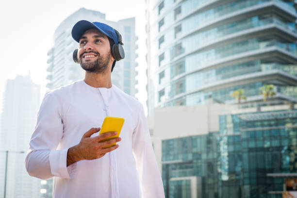Arabic man with kandora in Dubai Middle-eastern young adult wearing kandora walking outdoors in Dubai - Arabic man wearing the traditional emirates clothes emirati culture photos stock pictures, royalty-free photos & images