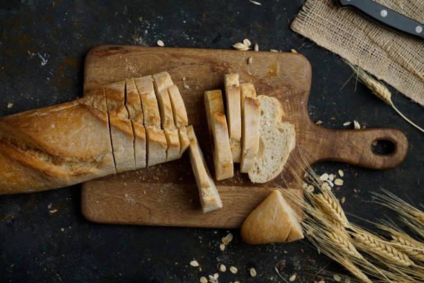 Fresh Baguette Bread Loaf Cut into Slices Slicing French baguette bread loaf and sheaf of wheat. loaf of bread stock pictures, royalty-free photos & images