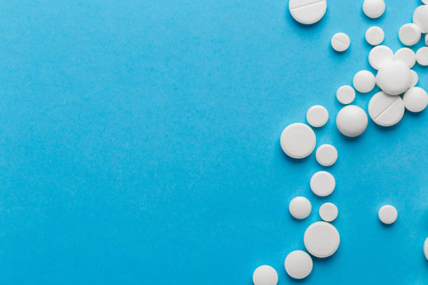istock scattered white pills on a blue table. Layout for special offers such as advertising or other ideas. The concept of medicine, pharmacy and healthcare. Space for copy. 1204273014