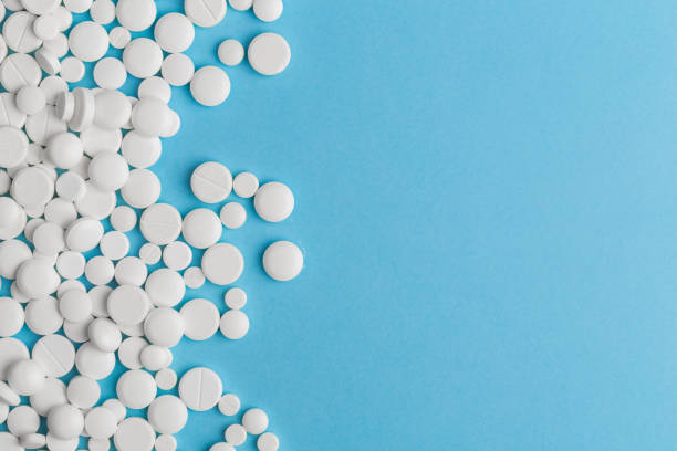 istock scattered white pills on a blue table. Layout for special offers such as advertising or other ideas. The concept of medicine, pharmacy and healthcare. Space for copy. 1204273268