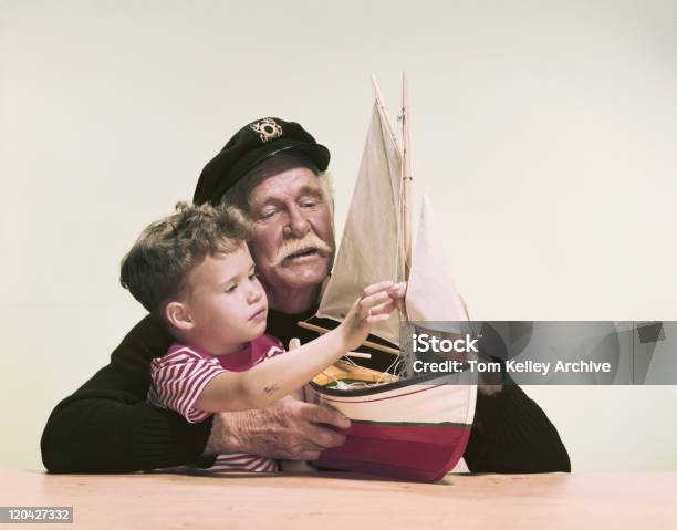 Avô E Neto Olhando Para O Modelo De Navio Contra Branco Bac - Fotografias de stock e mais imagens de De arquivo