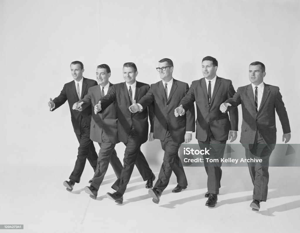 Businessmen extending hand to shake, smiling  Archival Stock Photo