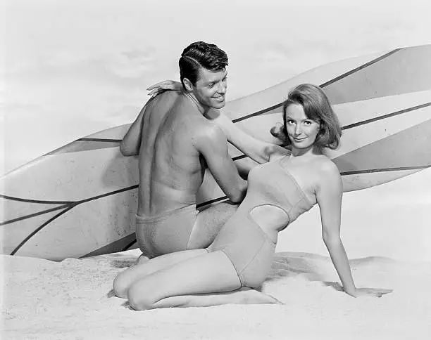 Photo of Young couple with surfboard on beach, smiling