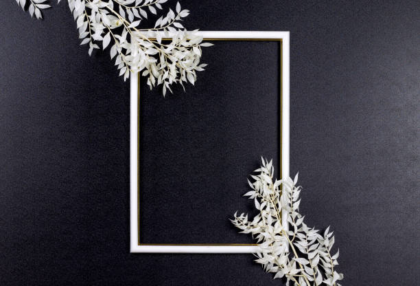 istock Decorative composition, white photo frame on a dark background, white branches with leaves. Flat lay, top view, copy space. 1204273950
