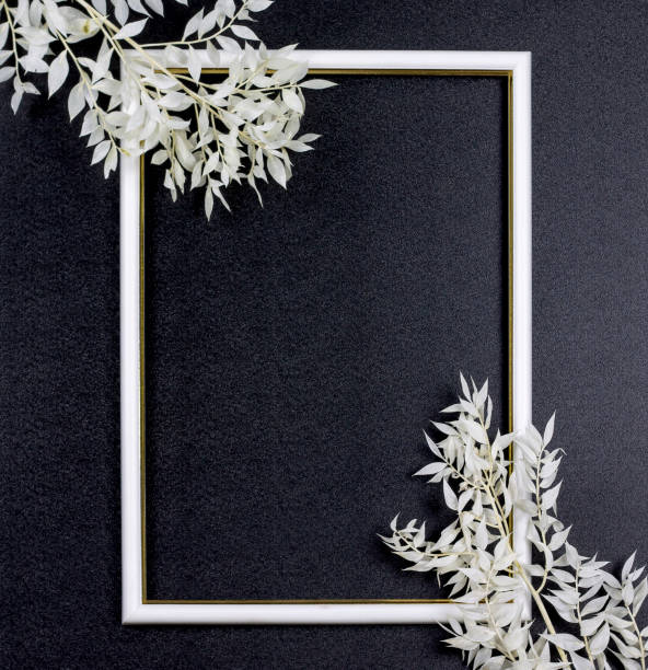istock Decorative composition, white photo frame on a dark background, white branches with leaves. Flat lay, top view, copy space. 1204274057