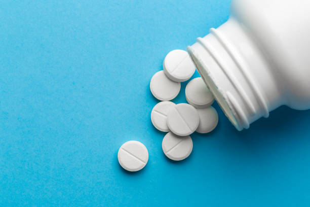 istock scattered white pills on a blue table. Layout for special offers such as advertising or other ideas. The concept of medicine, pharmacy and healthcare. Space for copy. 1204274184