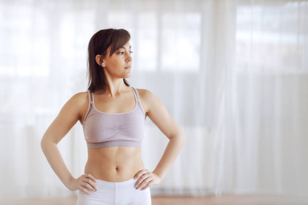 istock Young attractive fit brunette standing with hands on hips and looking away. 1204275643