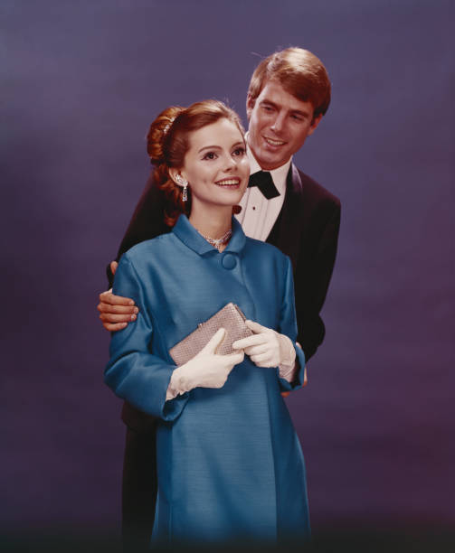 Couple in formal clothing standing against blue background, smiling  1968 stock pictures, royalty-free photos & images