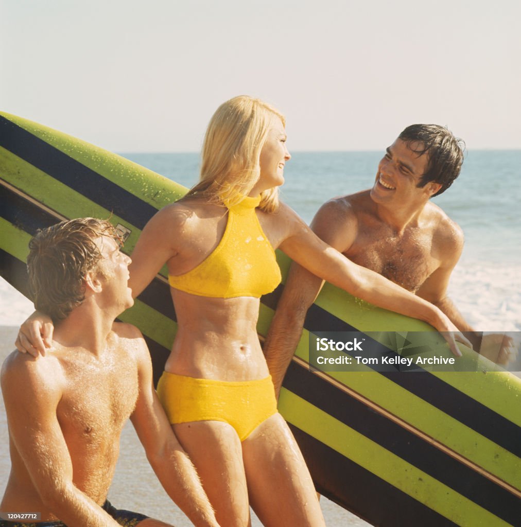 Giovane uomo e donna con tavola da surf sulla spiaggia, sorridente - Foto stock royalty-free di Di archivio
